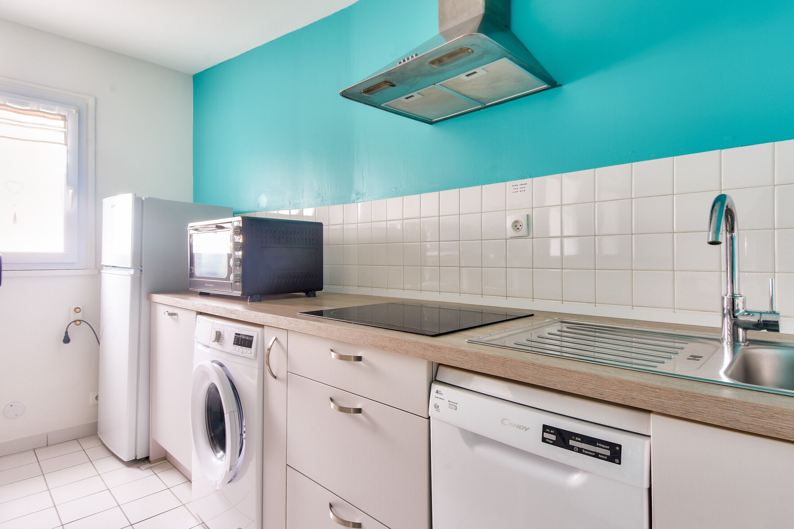 A compact kitchen with a washing machine, dishwasher, microwave, and a sink.