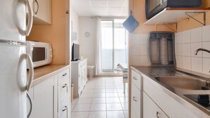 A kitchen with white cabinets, a microwave, a toaster, and a sink. - Cozy apartment, loggia, beach 100 m - 4 guests (Saint-Hilaire-de-Riez)