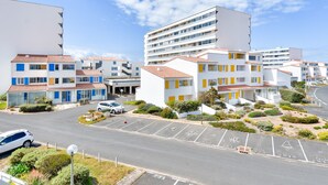 A modern building complex with multiple floors, parking spaces, and landscaped areas. - Cozy apartment, loggia, beach 100 m - 4 guests (Saint-Hilaire-de-Riez)