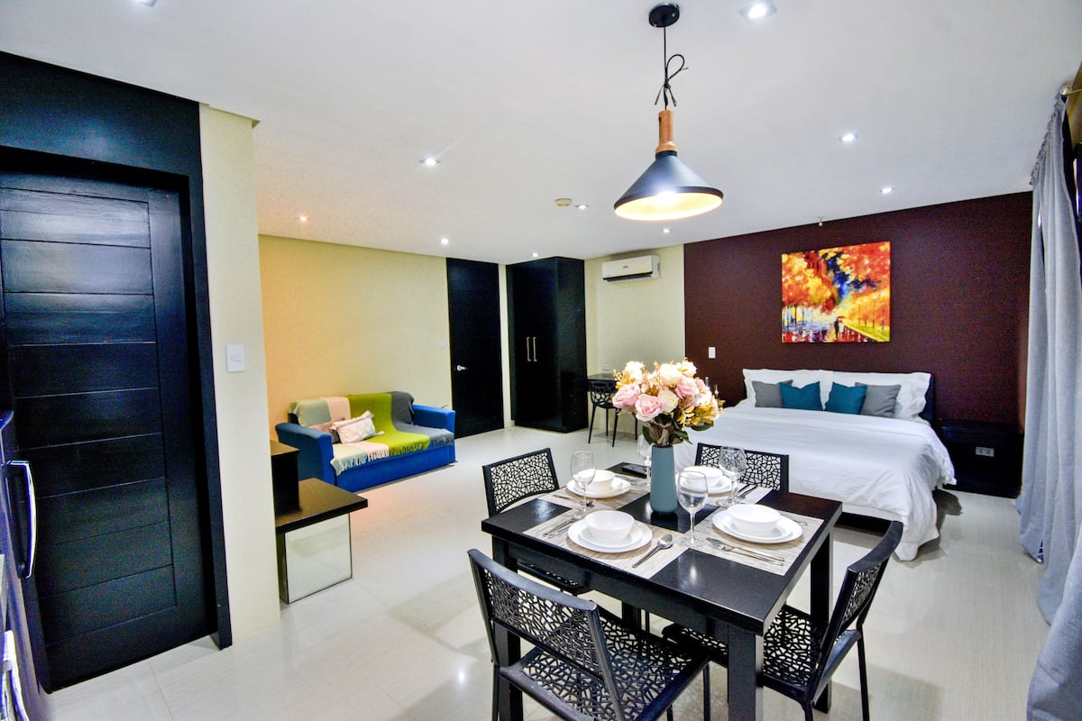 Une chambre d’hôtel moderne comprenant un coin repas, un canapé, un lit et un tableau au mur.