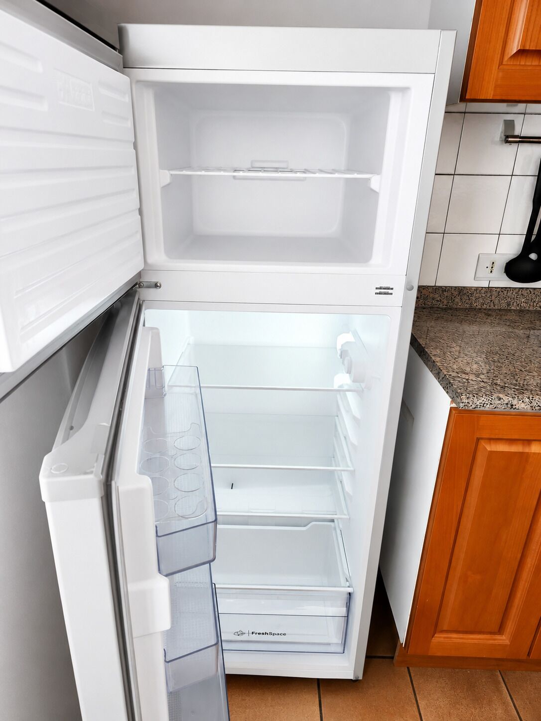 An open refrigerator with a fresh produce drawer, a water and ice dispenser, and a freezer compartment.
