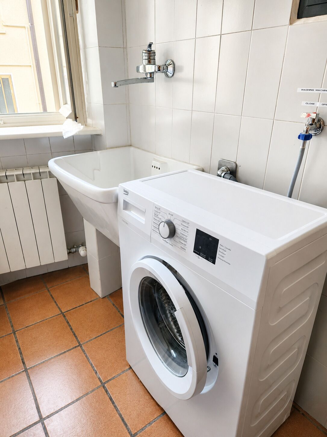 Un espacio reducido para la lavandería con lavadora y lavabo.