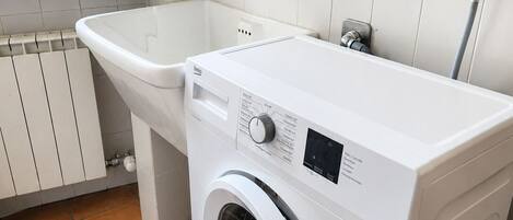 Un espacio reducido para la lavandería con lavadora y lavabo.