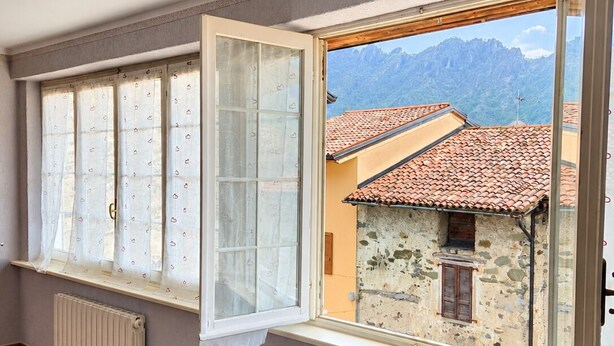 Habitació amb dues finestres, un radiador i vista a una muntanya.