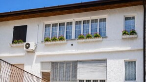 Un edifici amb nombroses finestres, algunes amb persianes, i amb jardineres als balcons.