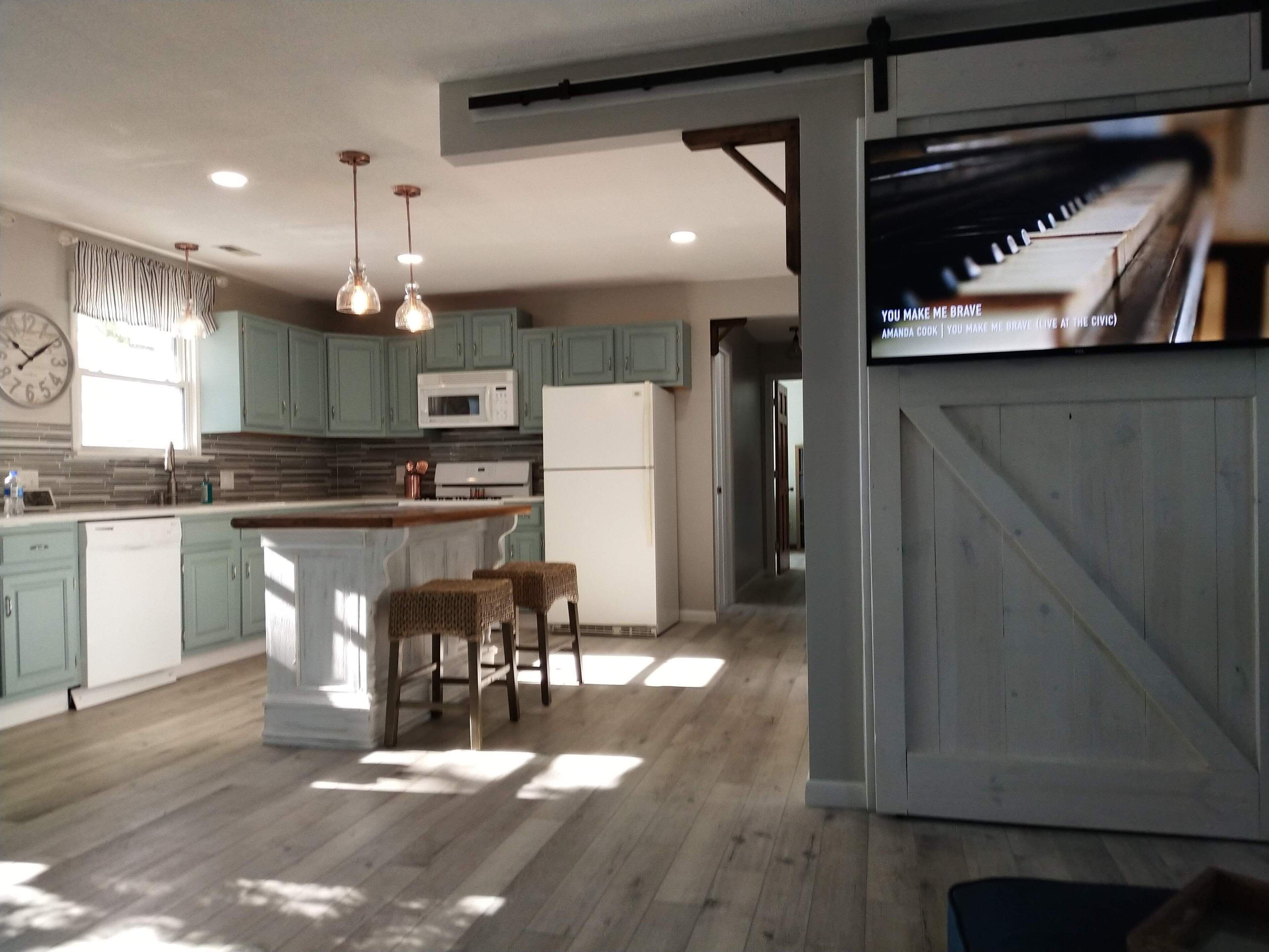 A kitchen with a central island, pendant lights, and a refrigerator.