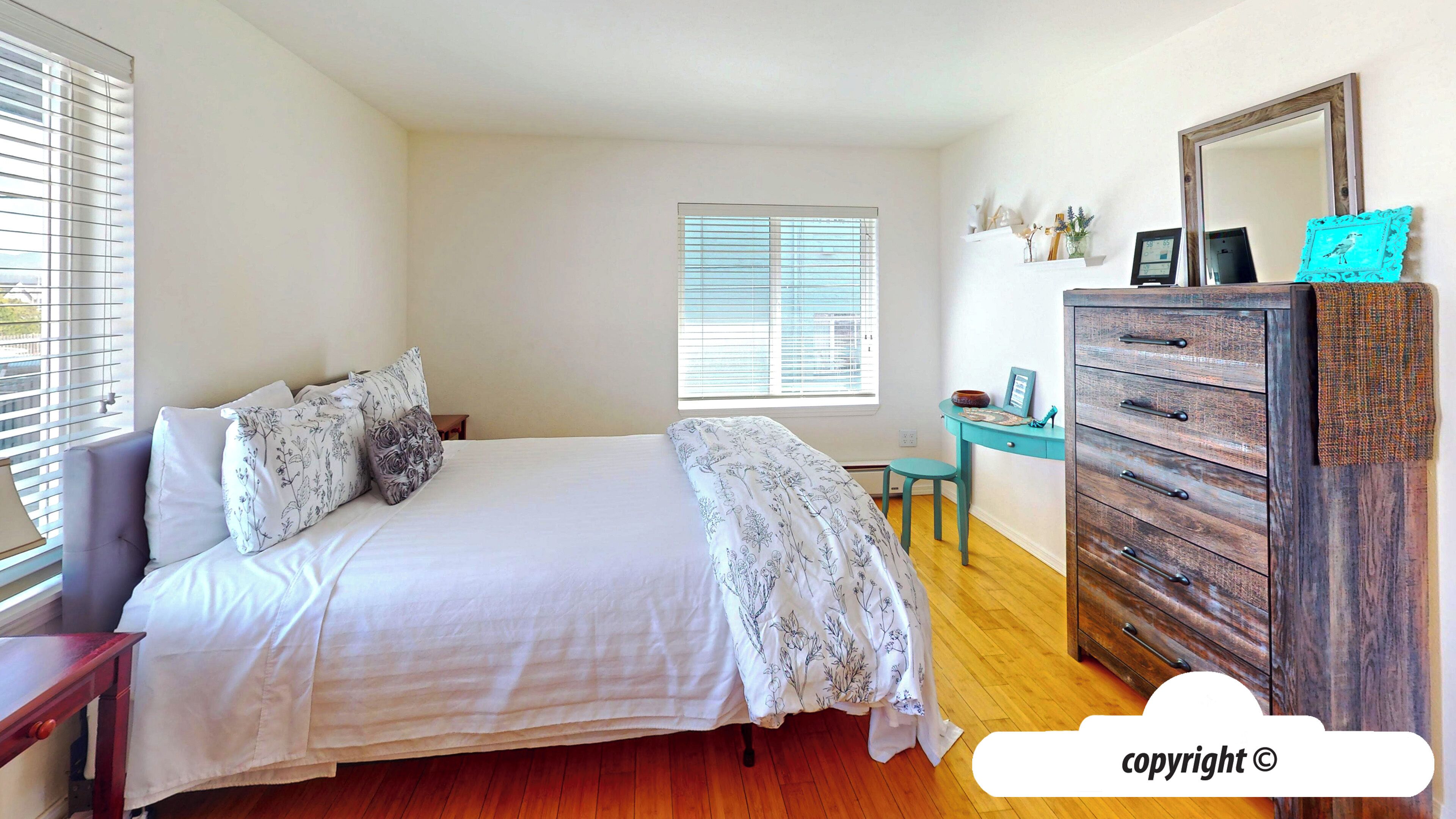 Un dormitorio con cama, cómoda, escritorio y ventana con persianas.