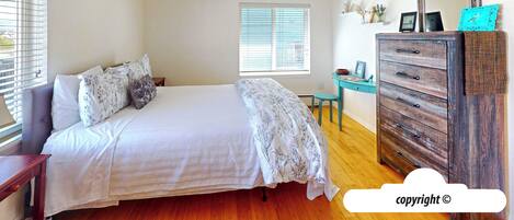 Un dormitorio con cama, cómoda, escritorio y ventana con persianas.