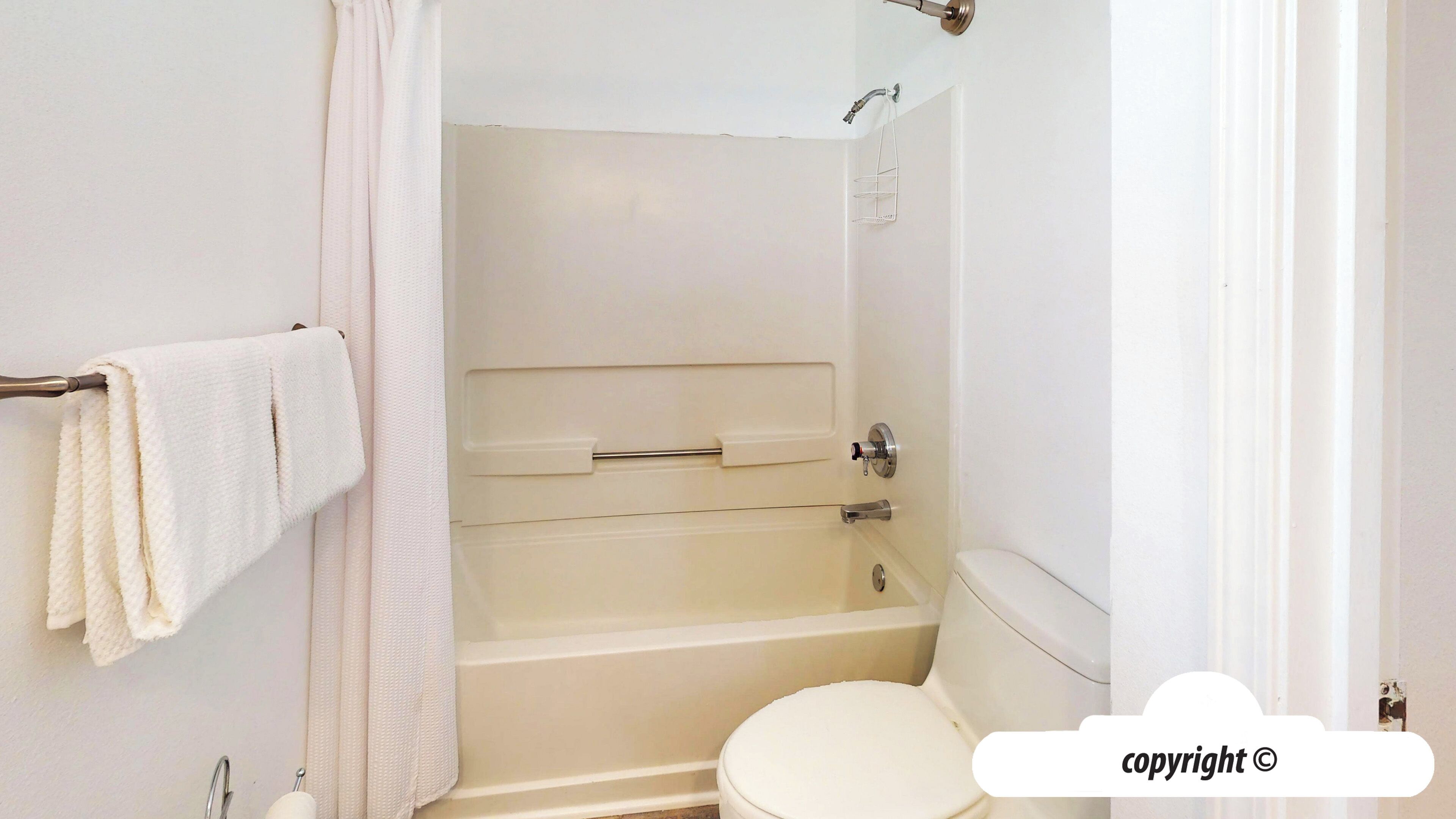 A bathroom with a bathtub, toilet, and towel rack.