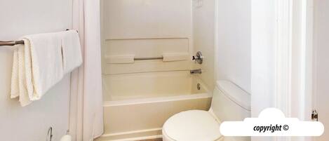 A bathroom with a bathtub, toilet, and towel rack.