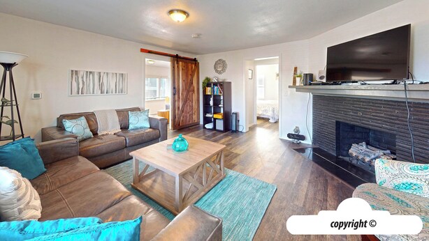 A living room with a sofa, coffee table, fireplace, and a television. - Margarita's at Seaside Beach (Seaside)