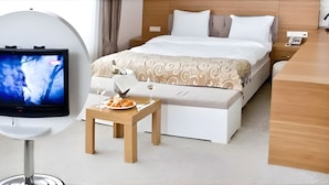 A hotel room with a bed, bedside table, and a TV on a modern stand. - ayvacık Hotel Restoran (Ayvacik)