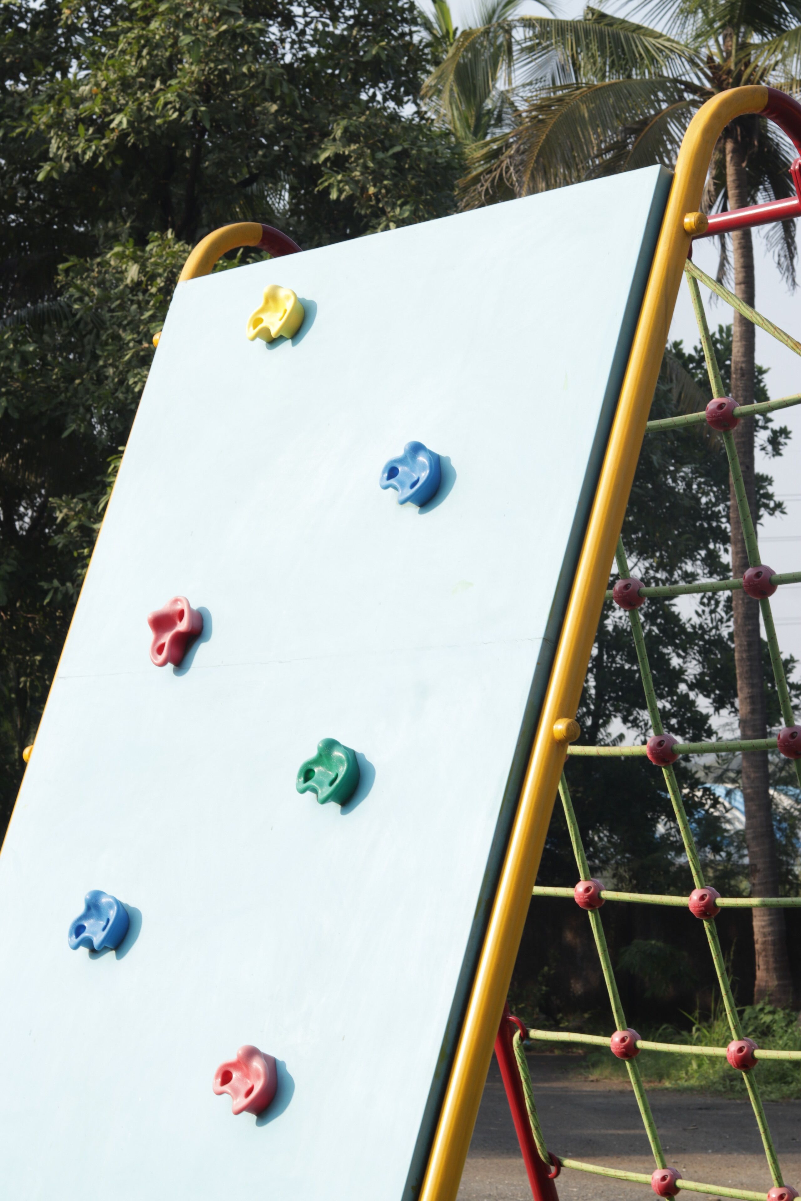 Una estructura para escalar con puntos de agarre de colores y una barandilla amarilla de seguridad.