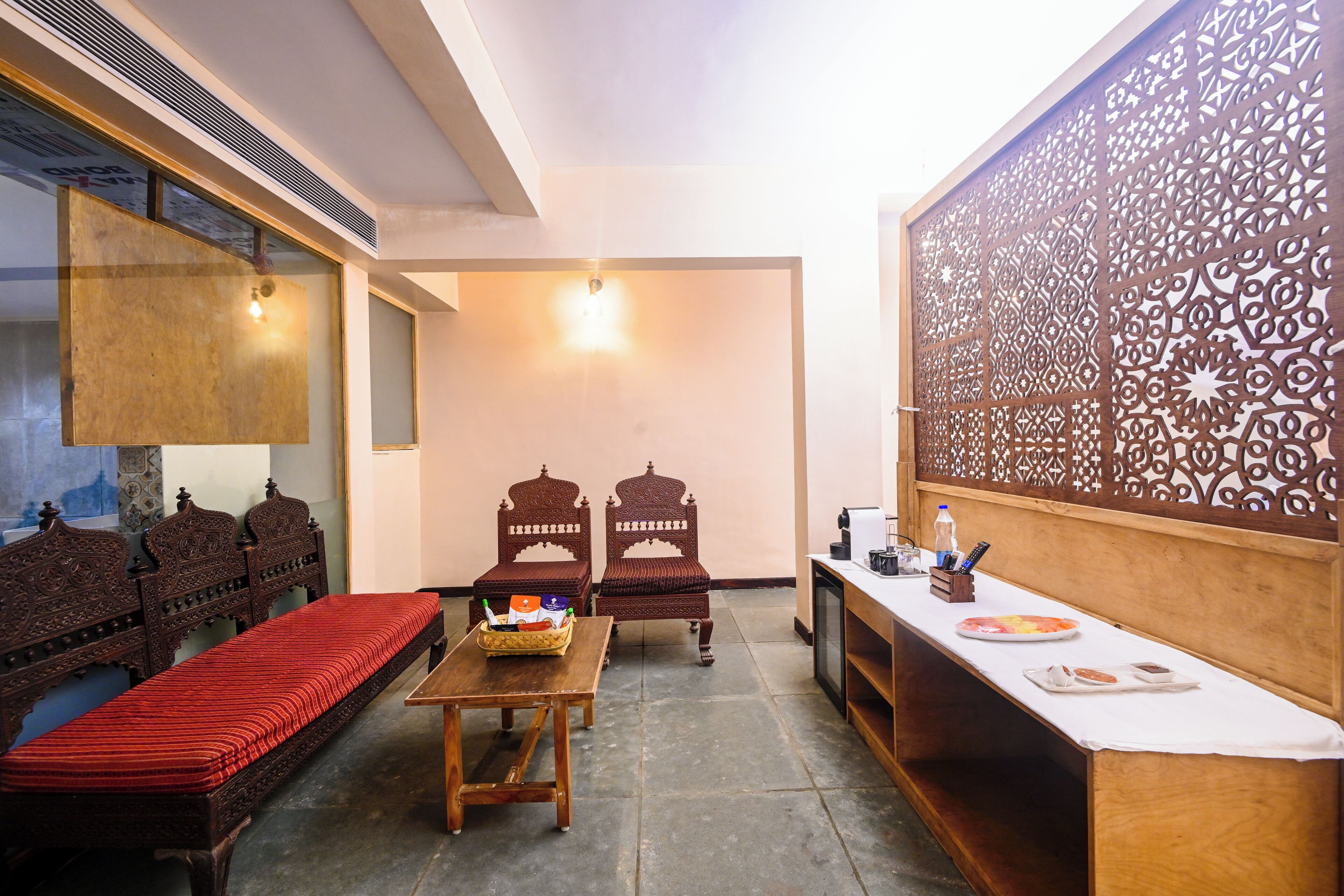 A traditional room with a sofa, two chairs, a small table with a basket, a television, and a decorative partition.