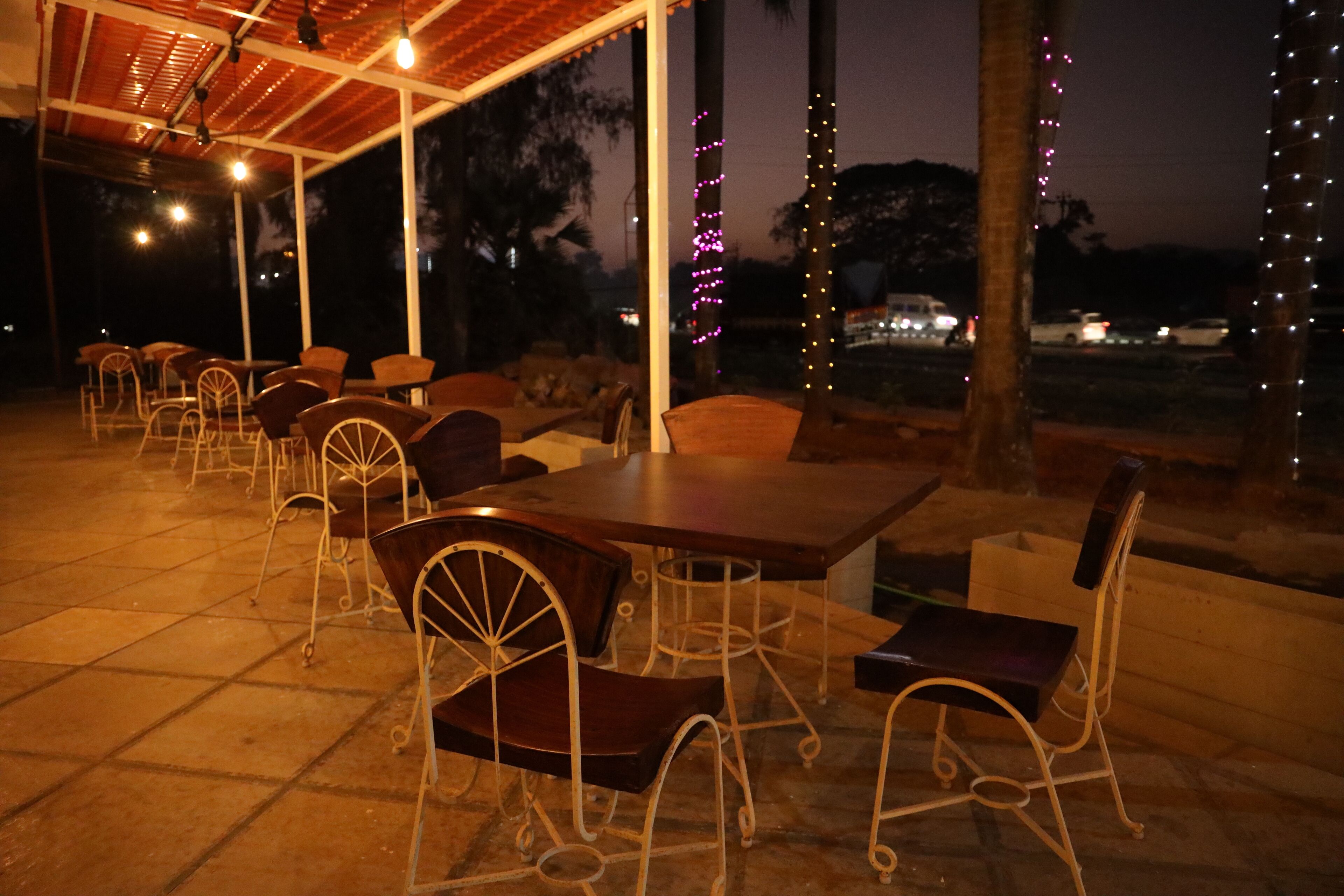 An outdoor seating area with tables and chairs, a tiled floor, and string lights.