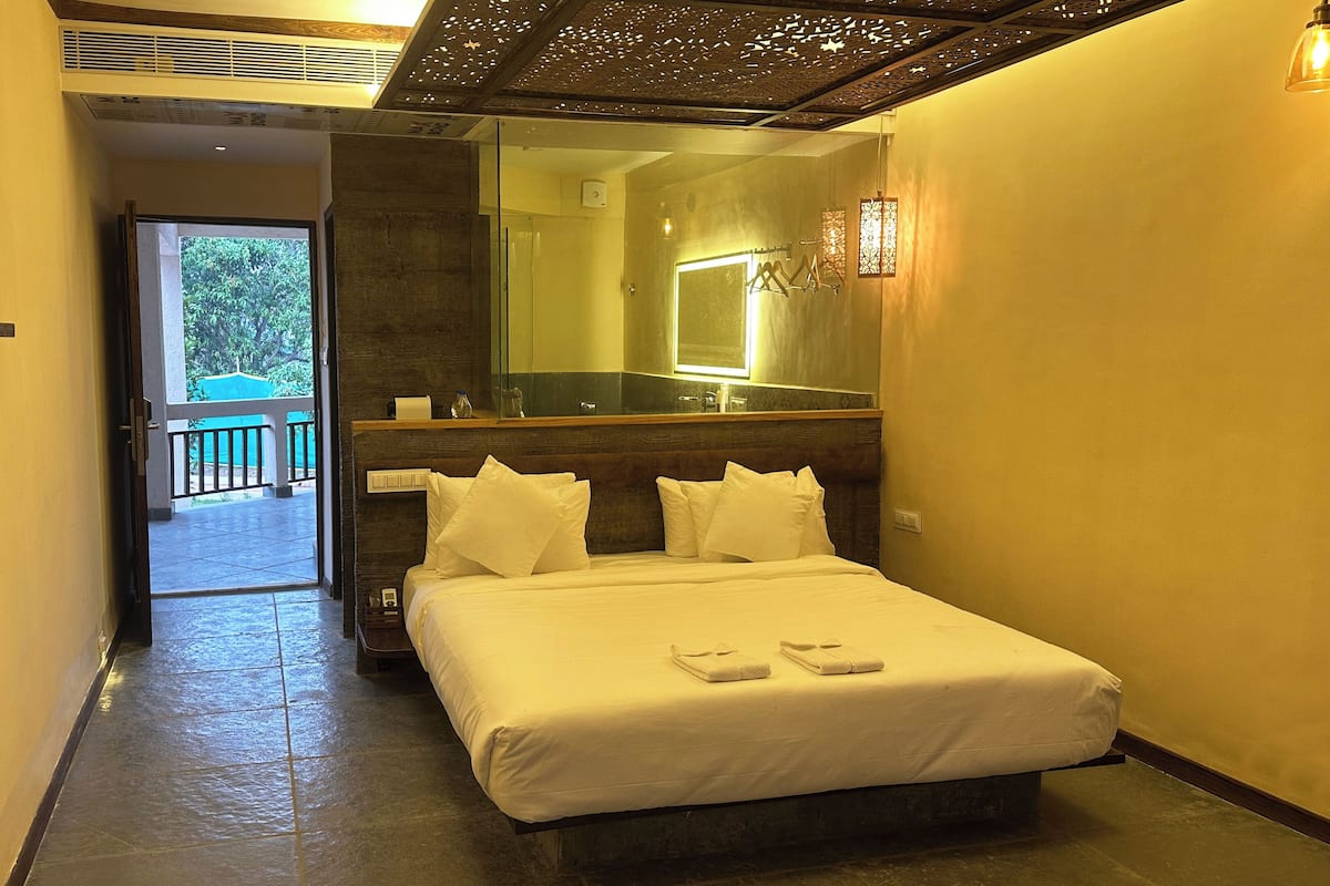 Une chambre d’hôtel avec un lit, un grand miroir et une vue sur un balcon.