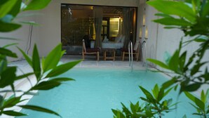 An indoor swimming pool with clear water, surrounded by a tiled floor and wooden chairs. - Avhyay Resort (Vasai)