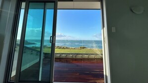 A room with a large sliding glass door leading to a deck with a view of the ocean. - Relax at "Rocky Point" - a private, modern home w/cliff views of the Tasman Sea. (Cape Foulwind)