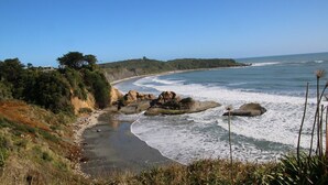 A coastal landscape with a beach, rocky outcrops, and a clear blue sky. - Relax at "Rocky Point" - a private, modern home w/cliff views of the Tasman Sea. (Cape Foulwind)