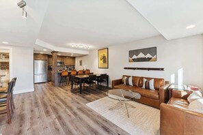 A spacious living area with a dining table, sofa, and kitchen in the background.