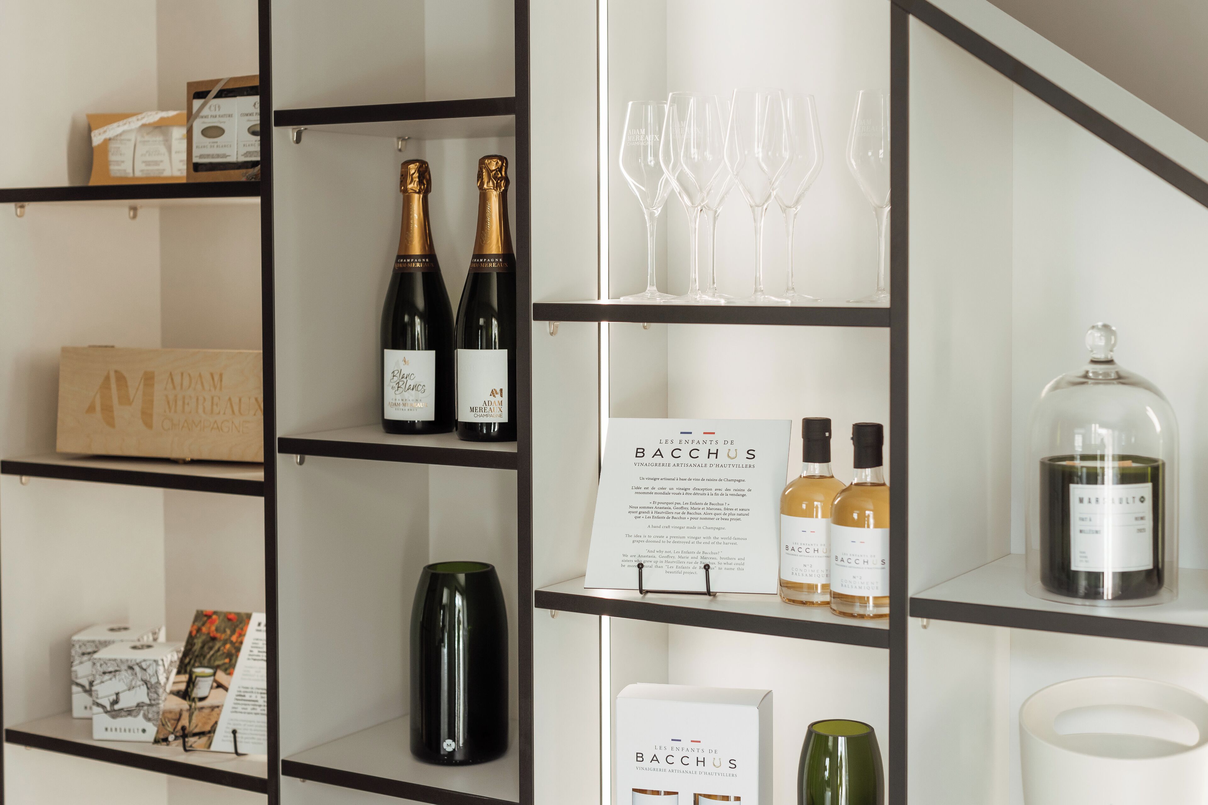 Exhibición de vino y copas con botellas y vasos en estantes.