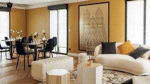 A modern living room with a sofa, ottomans, and a dining area with chairs and a table. - l'empreinte  (Verzenay)