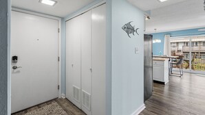 A modern kitchen with a large island, a dining area with a view, and a hallway with a door and closet.
