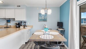 A dining area with a wooden table, white cabinets, and a blue wall.