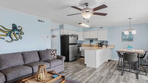 A compact living space with a kitchenette, a sofa, a dining area, and a ceiling fan.