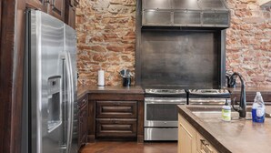 Une cuisine avec un mur en pierre, des appareils en acier inoxydable et des armoires en bois.