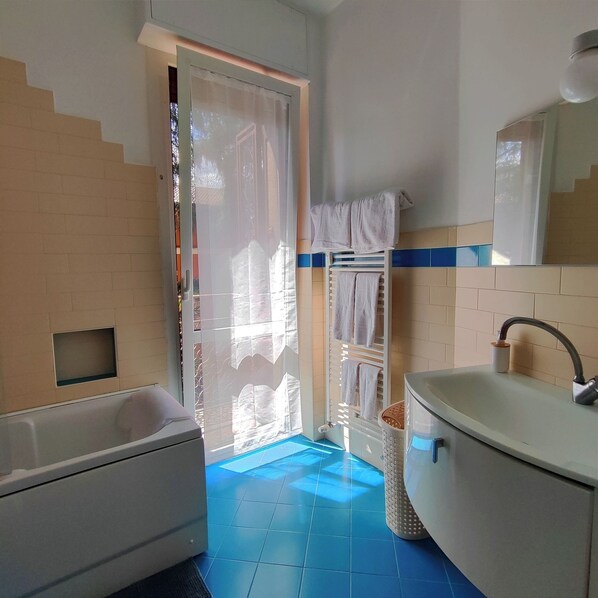 A bathroom with a bathtub, a sink, and a towel rack.