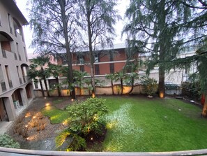 A courtyard with a lawn, trees, and a building with multiple windows and balconies.