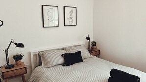 A bedroom with a bed, two framed pictures on the wall, a bedside lamp, and a hanging light fixture. - Captivating 2-bed Cottage in Symonds Yat (Ross-on-Wye)