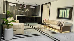 A modern living room with a sofa, a coffee table, and a potted plant. - Mini Palace Luxury Suites (Abuja)
