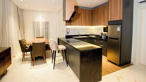 A modern kitchen with a central island, wooden cabinets, and stainless steel appliances. - Mini Palace Luxury Suites (Abuja)