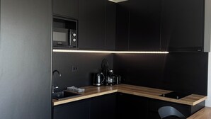 Une cuisine moderne avec des meubles de couleur sombre, un plan de travail en bois, un four à micro-ondes encastré et une machine à café.