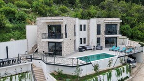 Une maison moderne à deux étages, dotée d’une piscine, d’un espace salon extérieur et d’un escalier menant à l’étage supérieur.