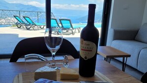 Une table avec une bouteille de vin Vranac, un verre, du fromage et un couteau, le tout posé sur une planche en bois.