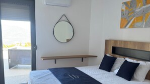 Une chambre à coucher avec un lit, une table de chevet, un miroir et un tableau accroché au mur.