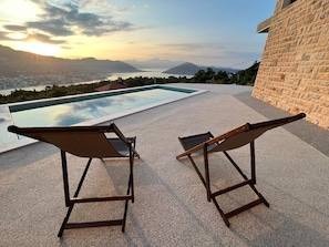 Ein Poolbereich mit zwei Liegestühlen und freiem Blick auf die umliegende Landschaft.