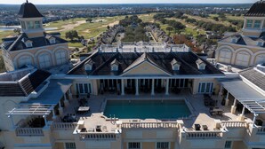 Een groot, elegant gebouw met een centraal gelegen zwembad, meerdere balkons en uitzicht op een golfbaan.