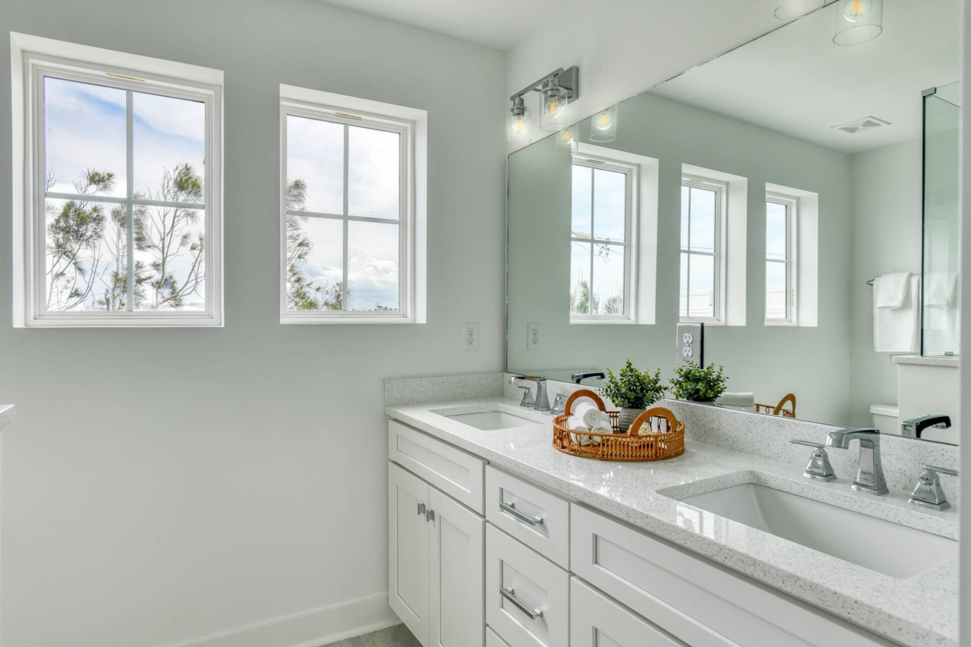A bathroom with two sinks, a large mirror, and windows.