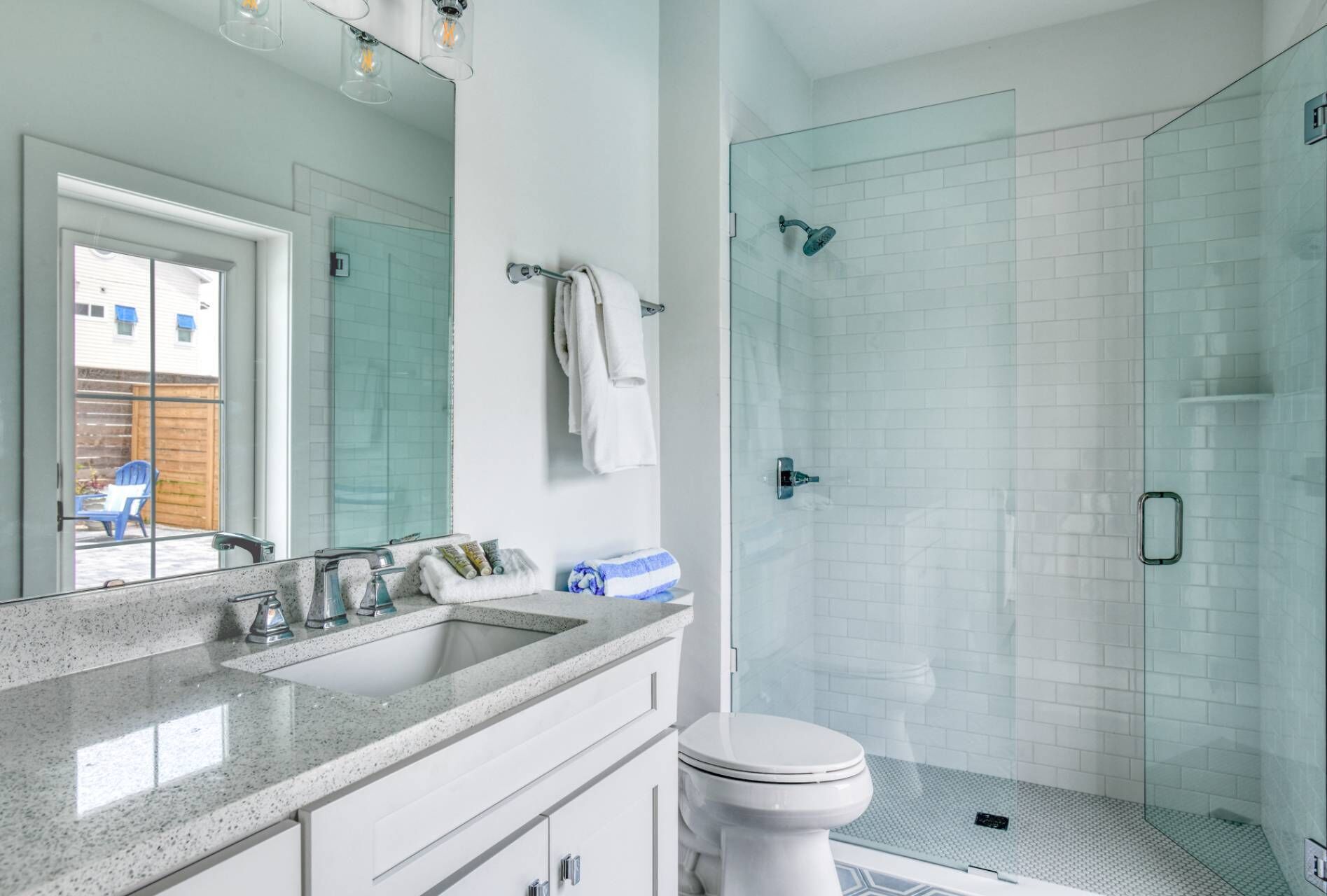 Une salle de bain moderne avec une douche à parois de verre, des toilettes blanches et un comptoir en granit avec un évier.
