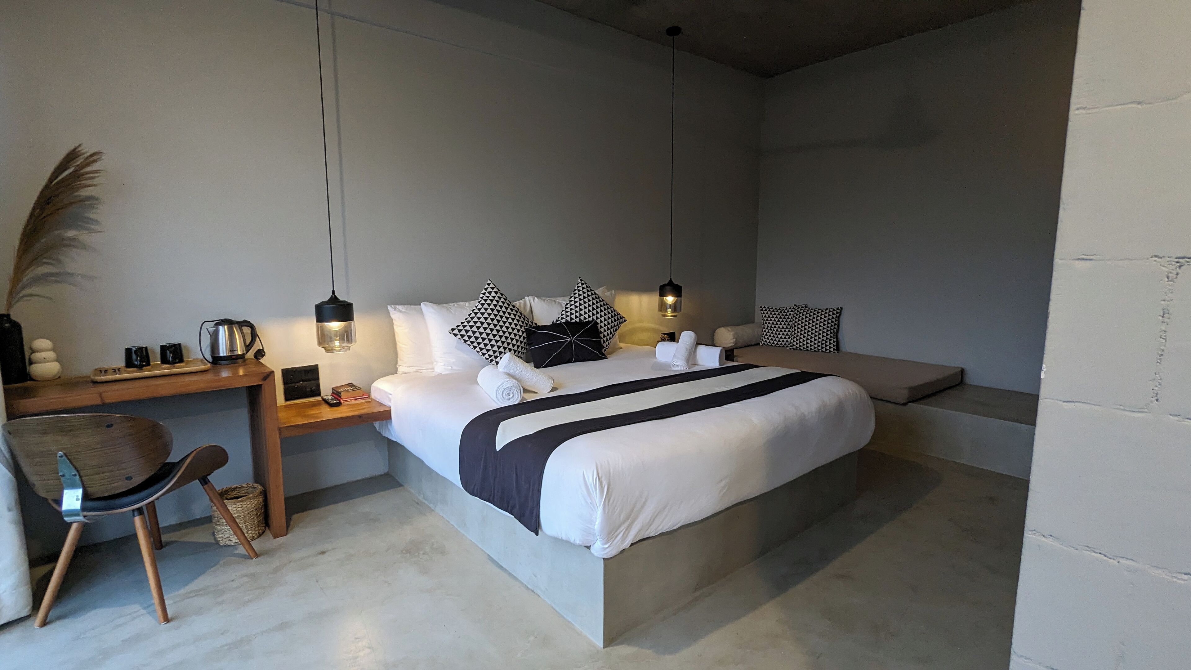 A modern bedroom with a bed, bedside tables, a desk, and a chair.
