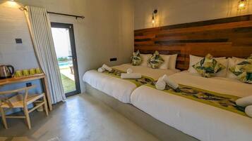 Quarto duplo com duas camas, cabeceira de madeira, uma mesinha com chávenas e vista para o exterior.