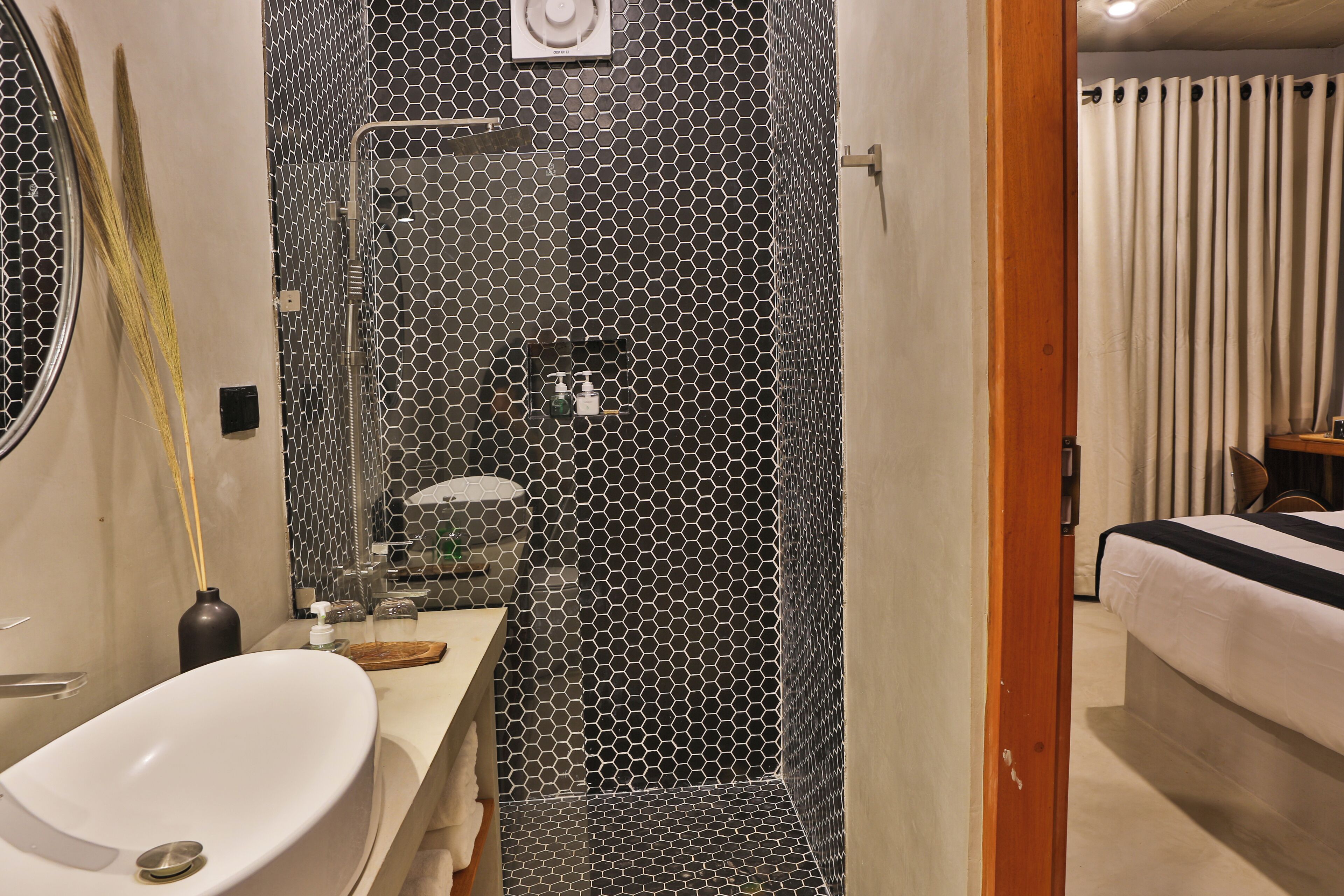 A modern bathroom with a hexagonal tile shower, a white sink, and a mirror.