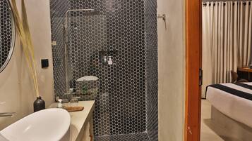 A modern bathroom with a hexagonal tile shower, a white sink, and a mirror.