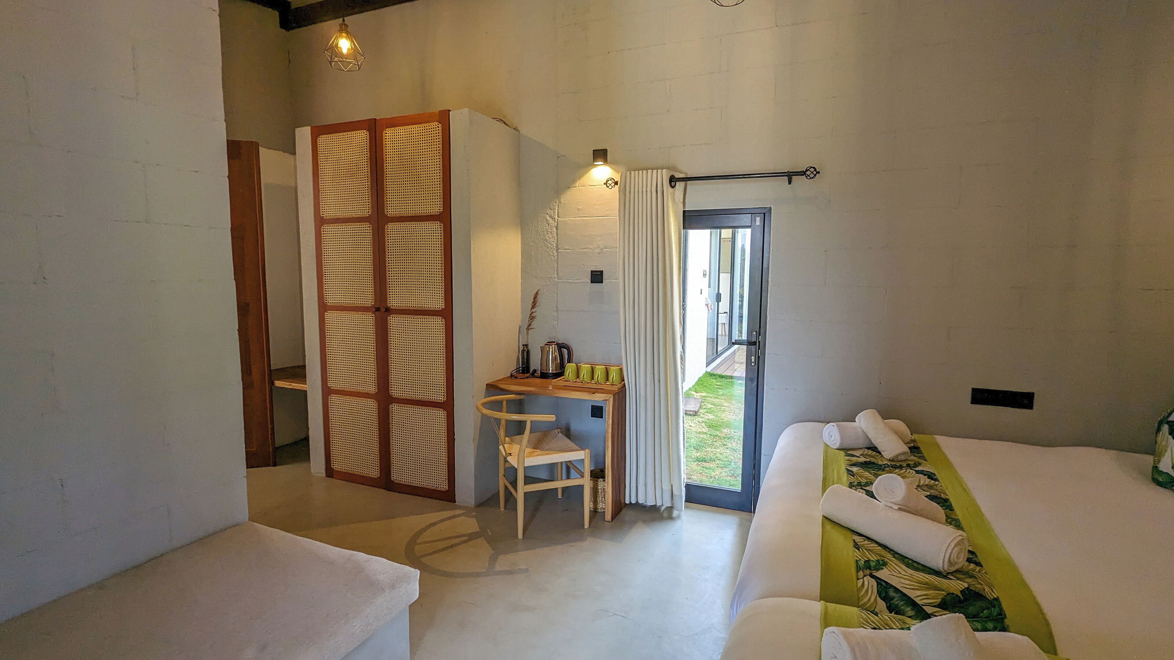 Habitación de hotel con cama, escritorio con silla, ventana con cortinas y vistas al exterior.