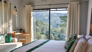 Une chambre dotée d’un grand lit, d’un bureau et offrant une vue sur un paysage montagneux.