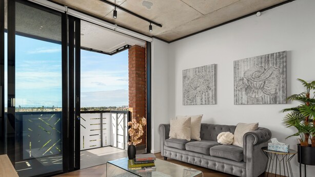 Un salon moderne avec un canapé gris, une table basse en verre et deux tableaux abstraits accrochés au mur.
